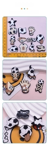Detail of soccer themed PVC shoe charms with black plastic back buckles and ruler for scale
