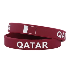 Close-up of wine red silicone sports wristbands with Qatar flag and white lettering