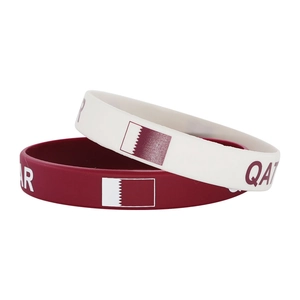 Close-up of silicone sport wristbands with Qatar flag and text on white background