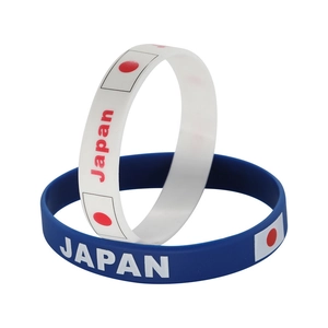 Close-up of white and blue silicone sports bracelets with Japan flag and text engraving