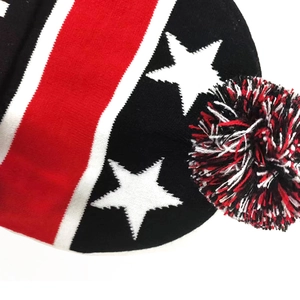 Close-up of knit winter hat featuring star patterns and a large tricolor pom-pom detail