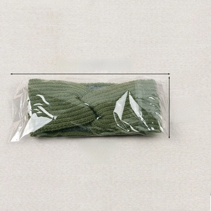 Detail showing dark green cable knit headband dimensions in clear plastic packaging