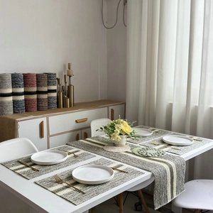 Detail of striped woven table runner and placemat set in grey, beige and yellow green