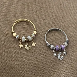 Detail view of gold and silver charm bracelets with moon star pendants on burlap fabric