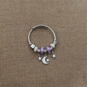 Detail of star and moon charms on a beaded stainless steel wire bracelet