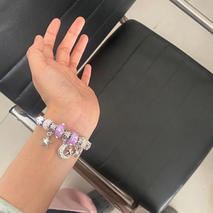Vintage star and moon charm bracelet with purple beads and crystal pendants on wrist