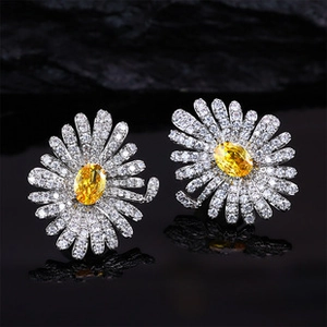 Detailed macro view of daisy enamel earrings with yellow gemstones and zircon petals
