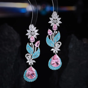 Detailed view of long waterdrop earrings with pink crystals and blue leaf accents