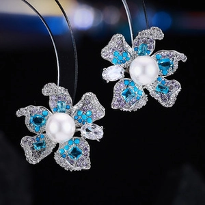 Macro view of crystal flower earrings with blue zircon petals and a large center pearl