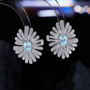 Macro view of daisy stud earrings featuring white zircons and a light blue stone