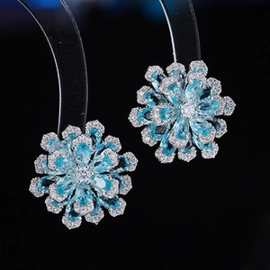 Macro detail of light blue water-drop gemstone flower earrings with zircon pavé inlay