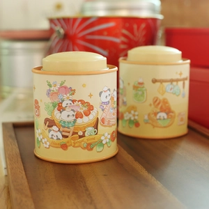 Close-up of cream round tin cans with cute panda illustrations on a wooden tray