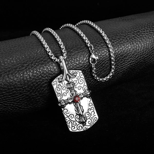 Detailed close-up of a silver gothic cross pendant with a red gemstone on a box chain