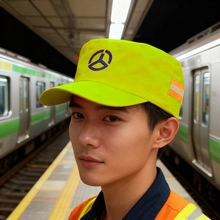Bright neon yellow high-visibility work cap featuring a blue logo in a train station