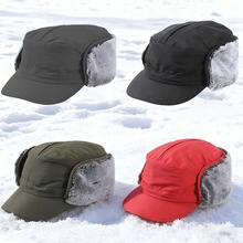 Detail view of four warm winter trapper hats in different colors displayed on white snow.