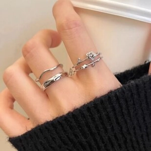 Close-up of vintage silver layered rings featuring wave textures and a rose vine charm