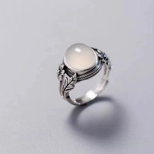 Close-up of vintage silver ring with oval white gemstone and floral leaf carvings