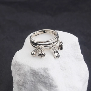 Detail of vintage silver open ring with lotus, bell and Fu character pendants