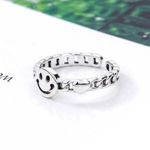 Retro silver chain ring featuring a smiley face and heart motif on a white background