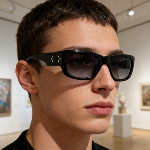 Close-up of black square polarized sunglasses featuring side gold floral rivets on male model
