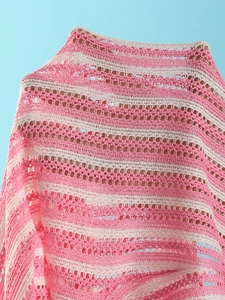 Détail d'un châle en maille crochetée à rayures roses et blanches et texture ajourée