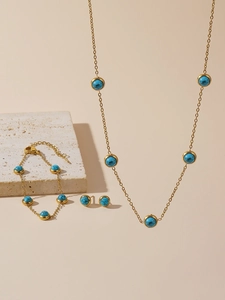 Detailed view of gold plated jewelry set with round turquoise stones on stone display