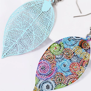 Macro view of hollow leaf-shaped earrings featuring blue metal texture and colorful patterns