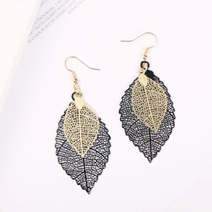 Detail of layered black and gold leaf earrings with intricate hollow-out metal design