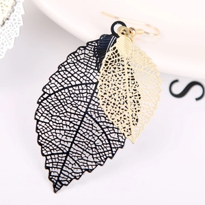 Macro view of gold and black layered hollow leaf earrings with intricate vein details