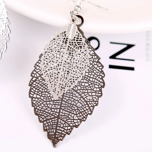 Macro detail of layered hollow leaf earrings with silver and gunmetal finish textures