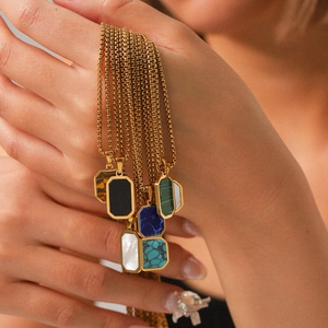 Detailed close-up of geometric gold-plated stainless steel pendants with natural stone inlays