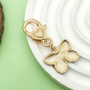 Golden butterfly metal keychain with heart lobster clasp on a textured white tray