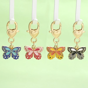 Colorful butterfly keychains with heart-shaped gold clasps in blue, purple, orange, and black
