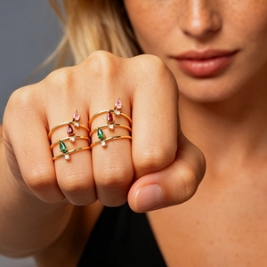 Detail of layered gold titanium rings with pear-cut pink and green zircon stones