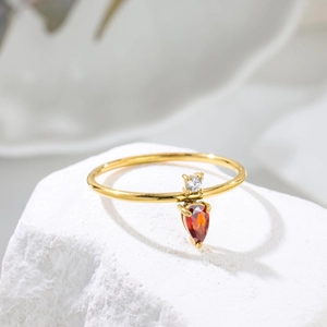 Detailed close-up of a two-tone zircon ring with round and pear-shaped stones on white stone