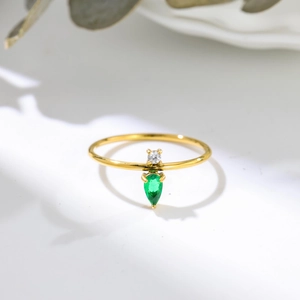 Close-up of a gold ring featuring a round white zircon and a pear-shaped green gemstone