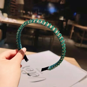 Detailed shot of emerald green crystal beads hand-woven with gold wire on a headband