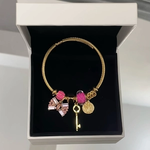 Gold stainless steel bangle with pink crystal bow and tree of life charm in jewelry box