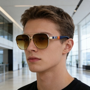 Detail of aviator sunglasses with gold metal frames and signature striped temple accents