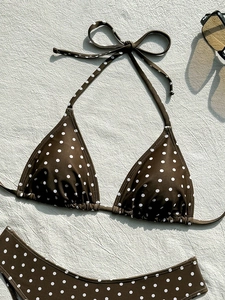 Bikini marrone a pois disteso con occhiali da sole su tessuto bianco testurizzato