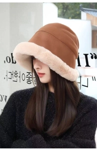 Side view of a thick plush bucket hat featuring brown suede and beige faux fur trim
