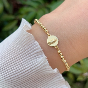 Detailed close-up of a 18K gold-plated beaded bracelet with a Virgin Mary pendant
