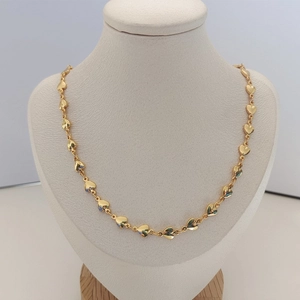 Detail shot of golden heart chain necklace displayed on a cream jewelry neck bust