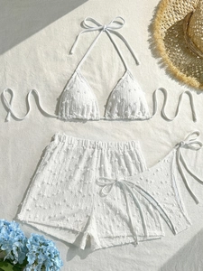 Dettaglio flat lay del bikini bianco a tre pezzi con tessuto testurizzato e accessori
