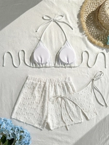Set bikini bianco tre pezzi steso in piano con tessuto testurizzato e lacci regolabili