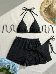 Dettaglio del bikini nero 3 pezzi con texture a bolle e decorazioni con pompon