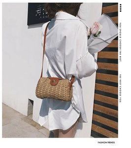 Detail of hand-woven straw crossbody bag with brown leather strap and gold metal lock