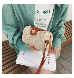 Detail of handmade woven beige straw crossbody bag with brown leather flap and metal lock