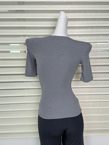Detail of grey fitted knit top featuring structured shoulder pads and ribbed texture