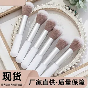 Close-up of fluffy mushroom head makeup brushes with soft white bristles and silver ferrule